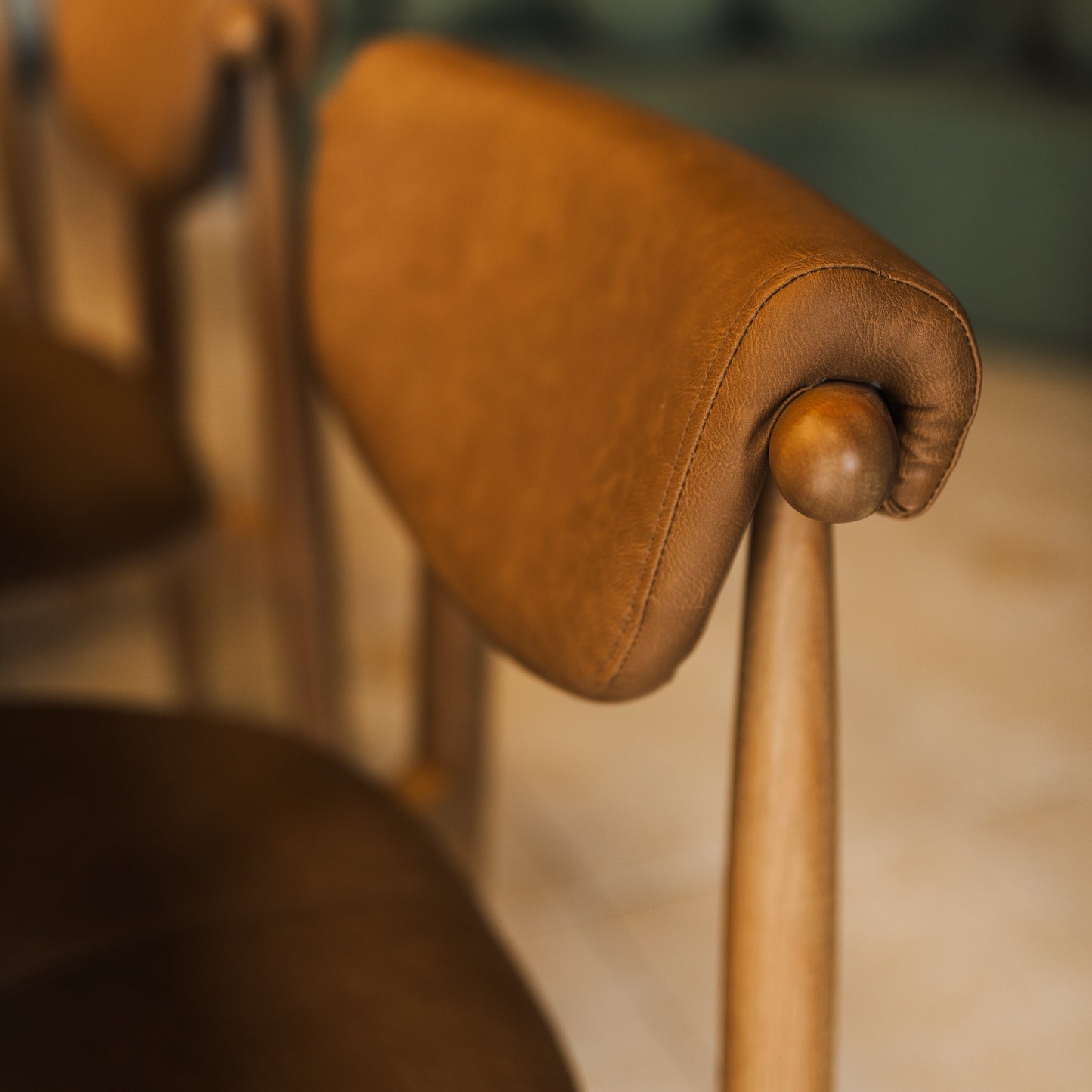 Cadeira de jantar com detalhe do encosto estofado caramelo e botão decorativo
