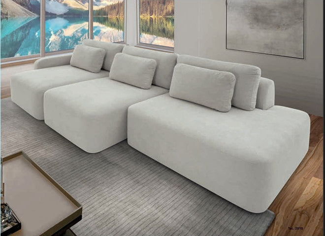 Sofá retrátil cinza claro com chaise, assentos largos e almofadas decorativas